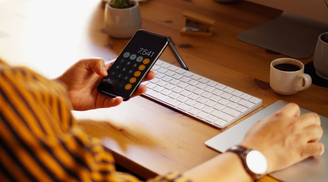 A person making a payment on their cell phone, related to an installment loan payment calculation.