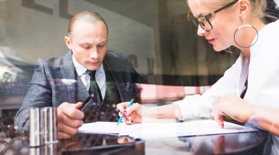 A man and woman sit at a table, reviewing bankruptcy papers together, appearing focused and engaged in discussion.