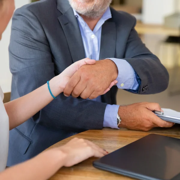 A man and woman shaking hands at a table, discussing a bankruptcy agreement.