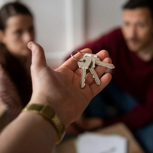A man holds keys in front of a woman and another man, symbolizing the resolution of a debt or financial obligation.