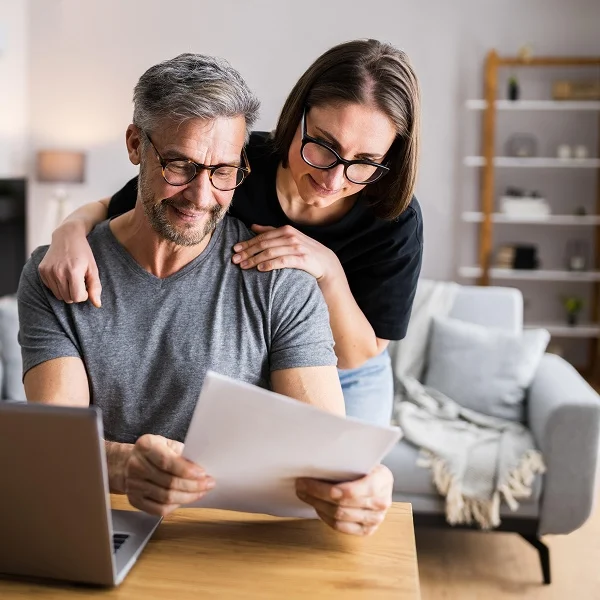 Man and woman reviewing documents together on a laptop, focused on their work.