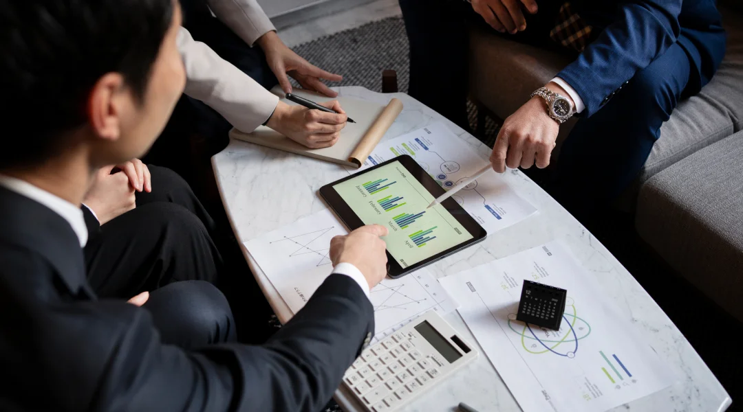 Business professionals collaborating on a tablet for financial management tasks in a modern office setting.