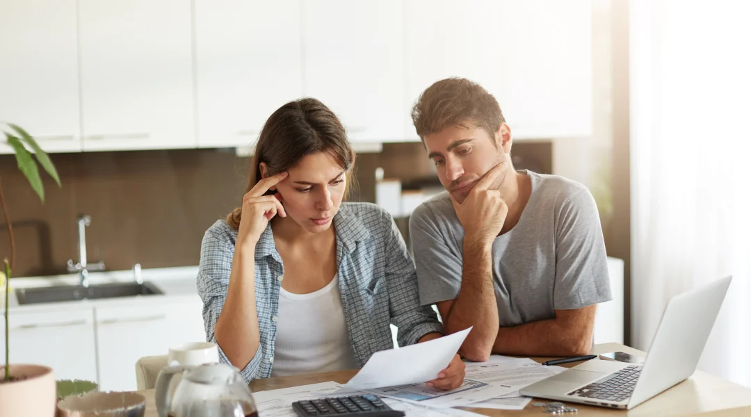 A man and woman review financial paperwork together at a table, discussing important financial decisions.