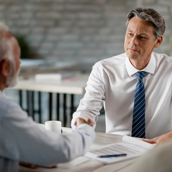 A man in a white shirt and tie shakes hands with another man, symbolizing a professional agreement in insolvency services.