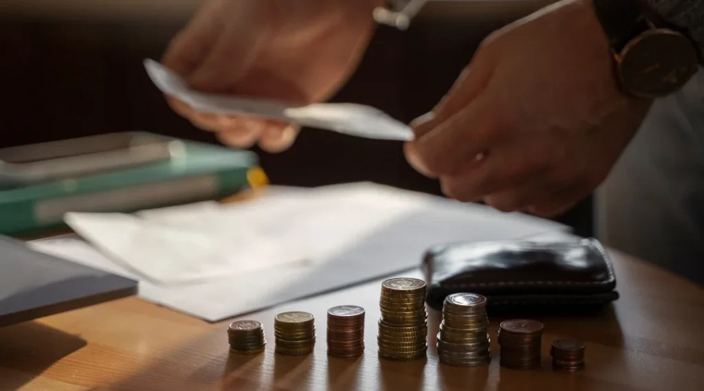 A person counting money on a table, symbolizing the process of debt consolidation and financial management.