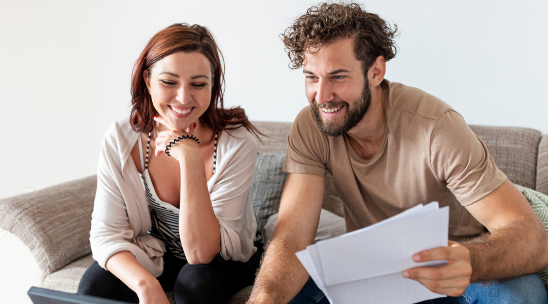 un couple souriant sur le canapé