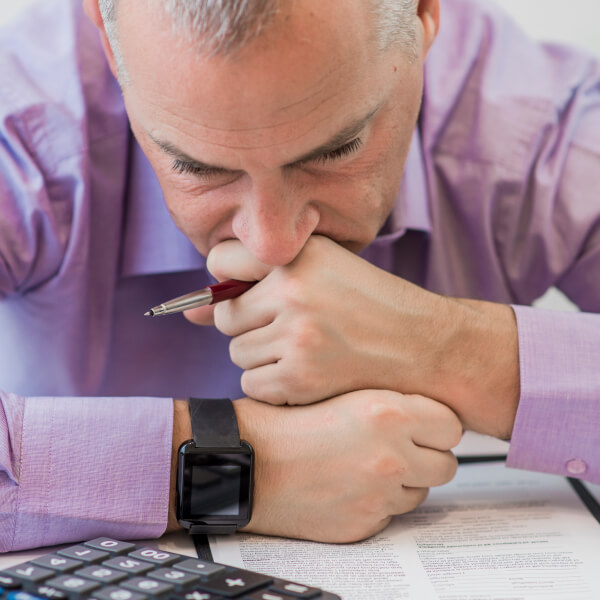 Un homme avec un stylo dans la bouche, semblant pensif ou en train de réfléchir.