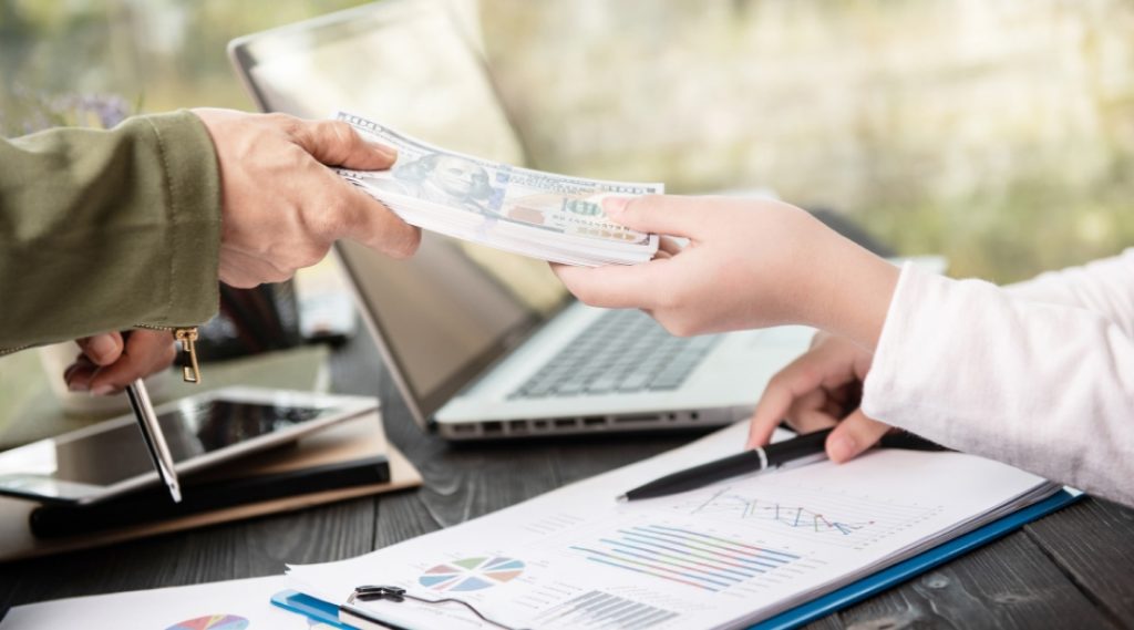 Conseiller financier expliquant la consolidation de dettes à Laval lors d’une rencontre avec un client analysant des documents financiers